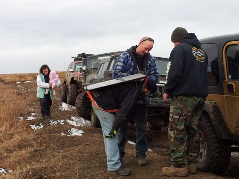 1990 Chevrolet Suburban - Several off-road vehicles are parked on a muddy track, with people interacting near them.