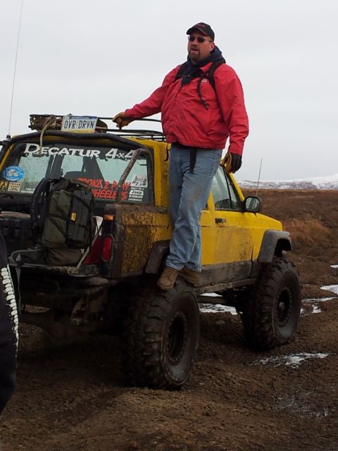 1990 Chevrolet Suburban - Man stands on a modified yellow Jeep Cherokee XJ, likely used for off-roading.