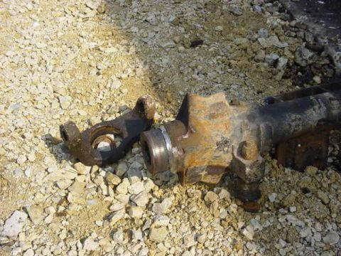 1992 Ford Bronco - A close-up view of a driveshaft component resting on a gravel surface, with a Supermotors.net logo in the corner.