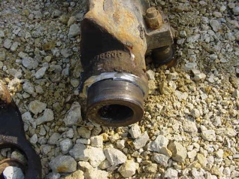 1992 Ford Bronco - Close-up of a heavily rusted metal part lying on a bed of gravel.