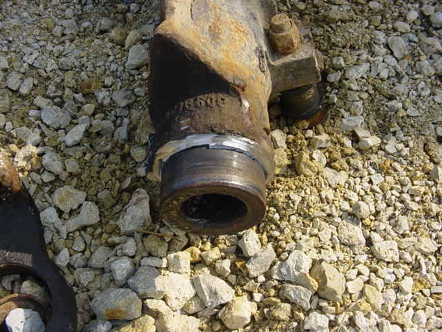 rusted metal component with a circular opening, resting on gravel