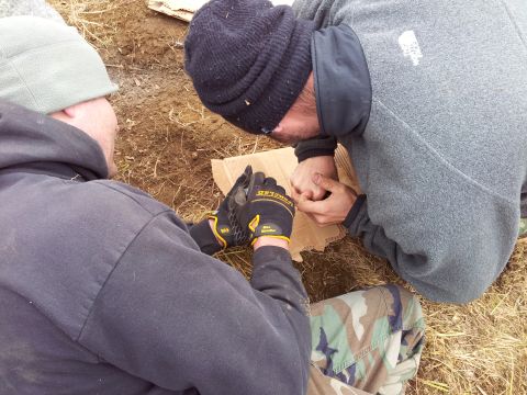 1990 Chevrolet Suburban - Two individuals are focused on a piece of cardboard, possibly examining or working on it outdoors.