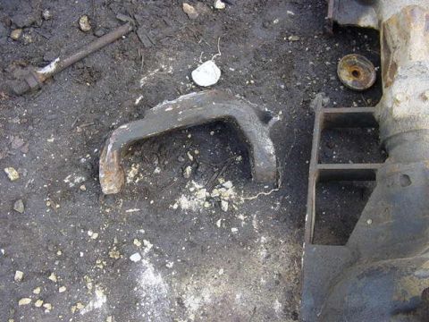 1992 Ford Bronco - A close-up view of a metal component resting on a soiled surface.