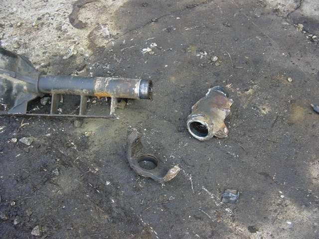 Broken axle components on dirty ground. Supermotors.net logo visible