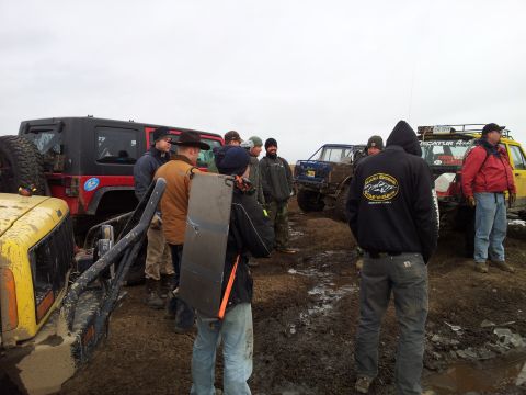 1990 Chevrolet Suburban - Several off-road vehicles and a group of people are gathered in a muddy, outdoor environment.