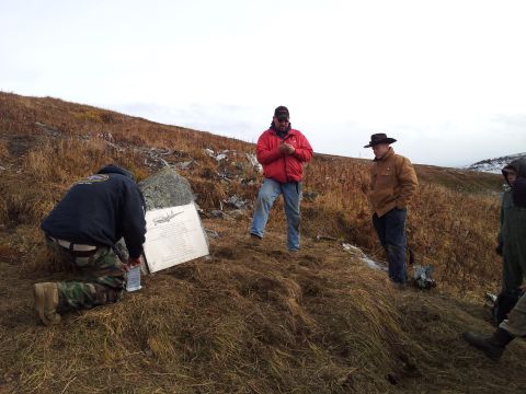 1990 Chevrolet Suburban - A group of people gather around a memorial plaque at a remote crash site, with a drawing of an airplane and extensive text.