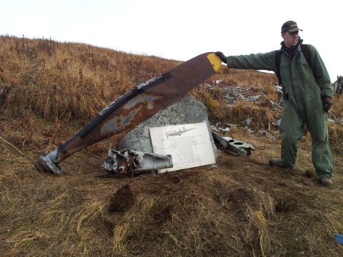1990 Chevrolet Suburban - A man stands next to wreckage, including a large propeller, at a crash site marked by a plaque.