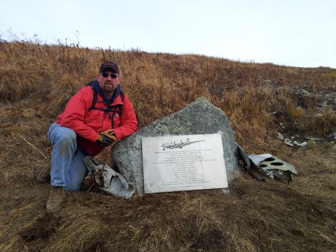 1990 Chevrolet Suburban - A man kneels beside a memorial plaque at a crash site, which includes a drawing of an airplane and text detailing the incident.
