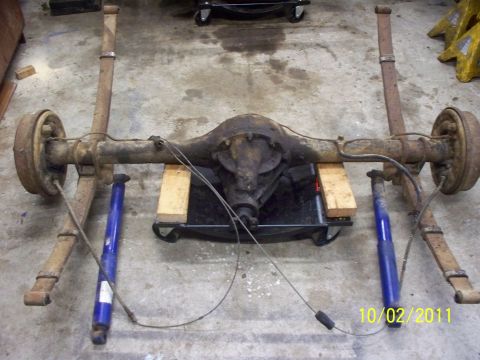 1990 Ford Bronco - This is a rear axle assembly with leaf springs and shocks, resting on a dolly in a garage.