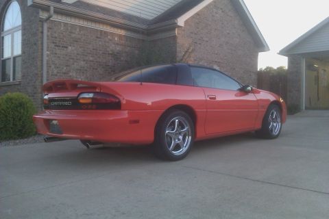 1999 Chevrolet Camaro - This red 1999 Chevrolet Camaro is parked in a driveway in front of a brick house.