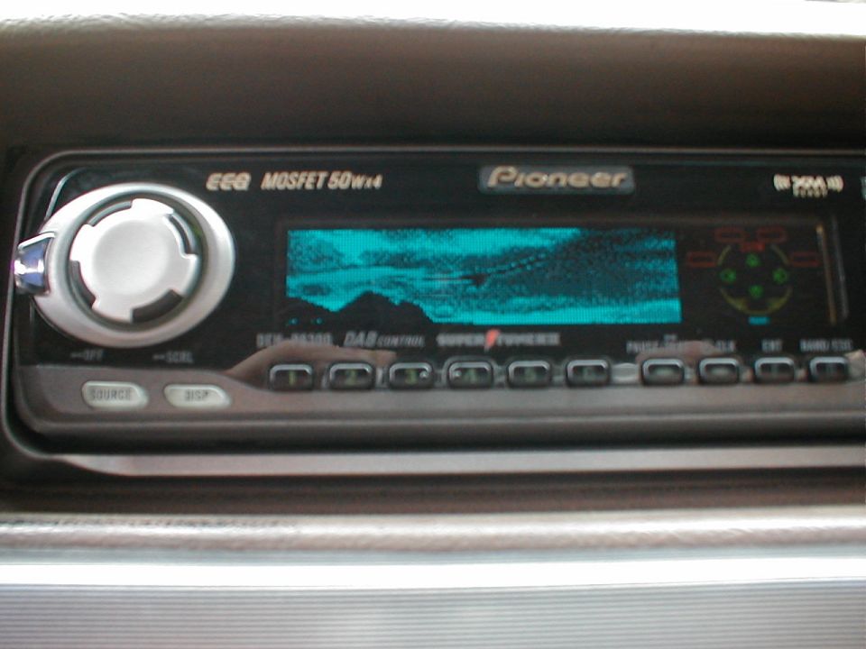 Pioneer aftermarket stereo head unit with teal display installed in a vehicle dash