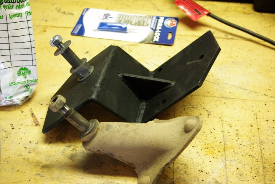 Black metal shock mount bracket with bolts and a beige suspension component