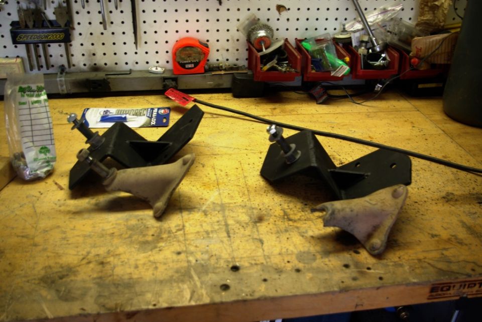 Two automotive shock mounts on a workbench with tools in the background