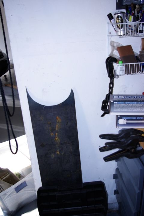 1995 Ford Bronco - A black metal part with yellow markings and a curved top edge is shown leaning against a white wall in a garage setting.