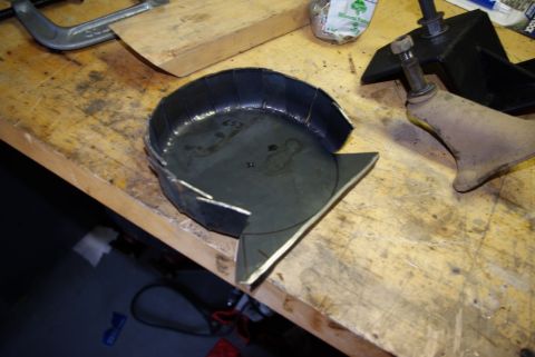 1995 Ford Bronco - A custom metal part, possibly for a vehicle suspension, sits on a workbench next to tools.