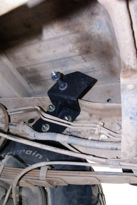1995 Ford Bronco - A close-up shows a black bracket and bolt assembly mounted to the underside of a vehicle's frame, near the rear suspension.