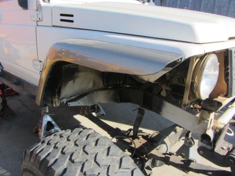 1987 Suzuki Samurai - Front fender and tire of a 1987 Suzuki Samurai, showing suspension and chassis details.