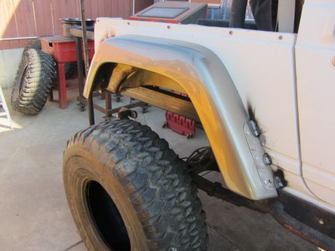 1987 Suzuki Samurai - A close-up view of a Suzuki Samurai's rear fender flare and tire, showing modifications.