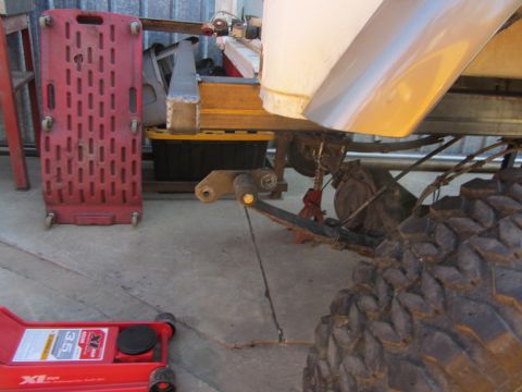 1987 Suzuki Samurai - The vehicle is supported by a floor jack and appears to be undergoing maintenance or modification.