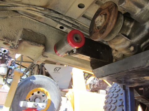 1987 Suzuki Samurai - Close-up view of a vehicle's undercarriage, highlighting a red and silver suspension part and a tire with a yellow rim.
