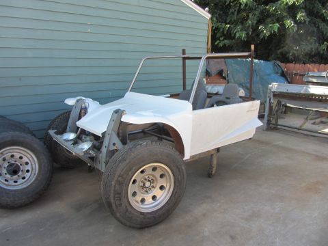 1987 Suzuki Samurai - A partially built off-road vehicle sits on a frame with its body panels attached and tires mounted.