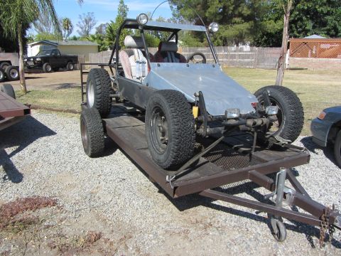 1987 Suzuki Samurai - A custom dune buggy is loaded onto a trailer, with a black pickup truck visible in the background.
