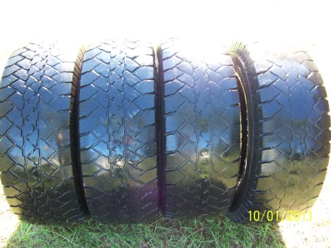 1986 Ford Bronco - Four tires are shown on grass with a date stamp and website watermark.