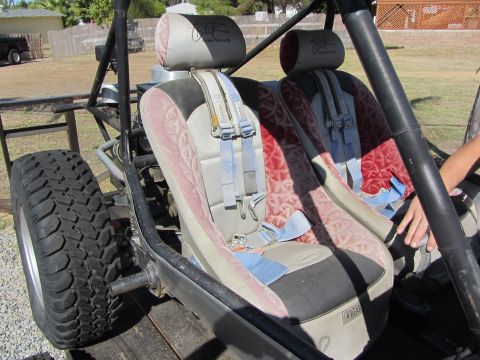 1987 Suzuki Samurai - The interior of a custom off-road buggy shows two seats with racing harnesses and a prominent roll cage structure.