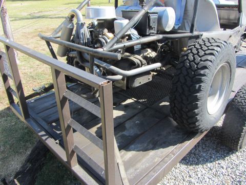 1987 Suzuki Samurai - Exposed engine and large off-road tire visible on a trailer.