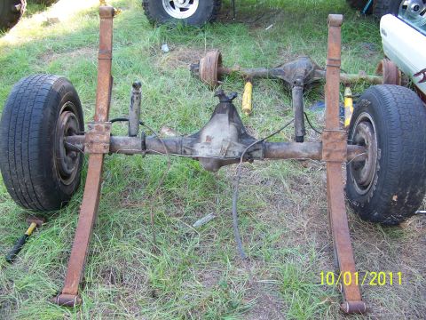 1986 Ford Bronco - A disassembled rear axle assembly with leaf springs and tires sits on the grass.