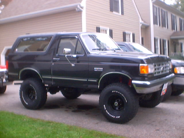 Lifted black Ford Bronco with BFGoodrich all-terrain tires parked in a driveway, passenger-side front view