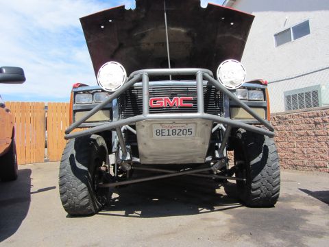 1987 Suzuki Samurai - GMC truck modified with a heavy-duty bumper and auxiliary lights, hood up.