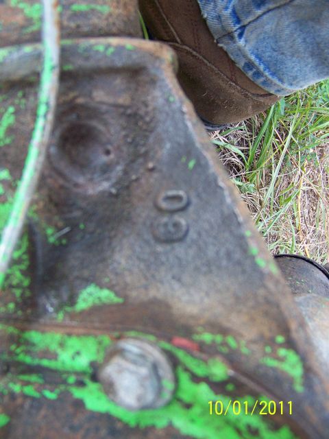 1986 Ford Bronco - Close-up of a metal part stamped with '60', with grass and a person's jeans visible.