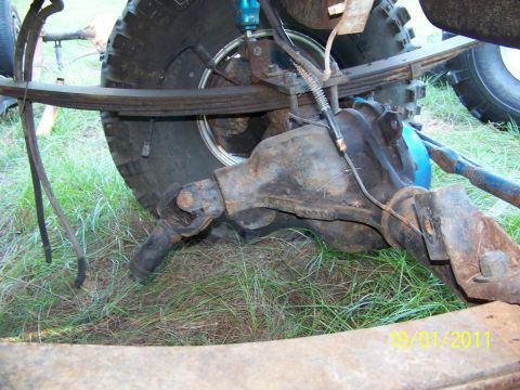 1986 Ford Bronco - Close-up view of the rear axle and suspension system, a blue shock absorber and leaf springs.