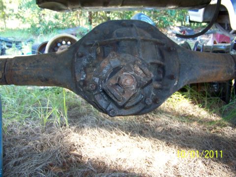 1986 Ford Bronco - Close-up of a heavily rusted rear axle differential assembly outdoors.