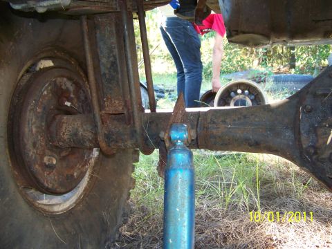 1986 Ford Bronco - Close-up view of the rear axle and suspension system of a vehicle, with a person visible in the background.