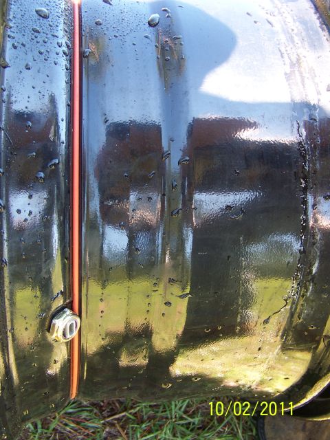 1986 Ford Bronco - Close-up of a black split rim with an orange accent ring and a chrome lug nut, reflecting the outdoors.