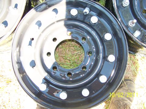 1986 Ford Bronco - Close-up of two truck wheels, one with a two-tone paint job, resting on grass.