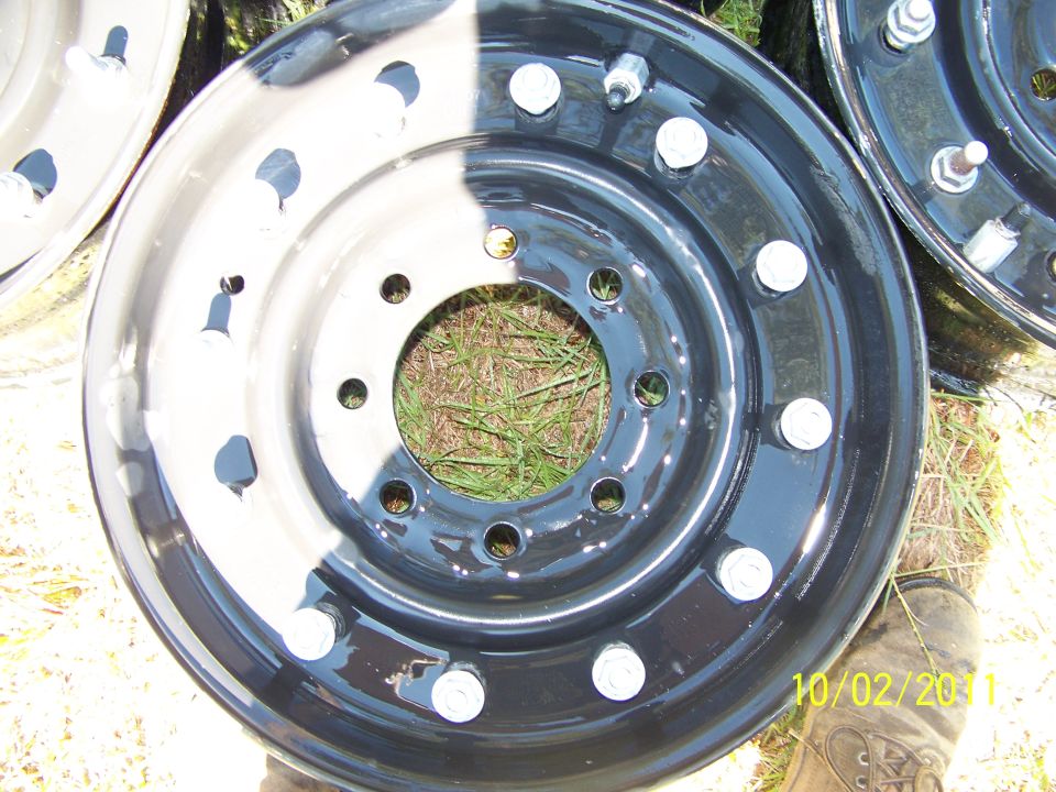 two black truck wheels with silver lug nuts, one wheel is half painted white