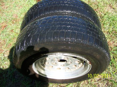 1986 Ford Bronco - A close-up view of two tires and rims resting on a grassy surface, with a date stamp visible.