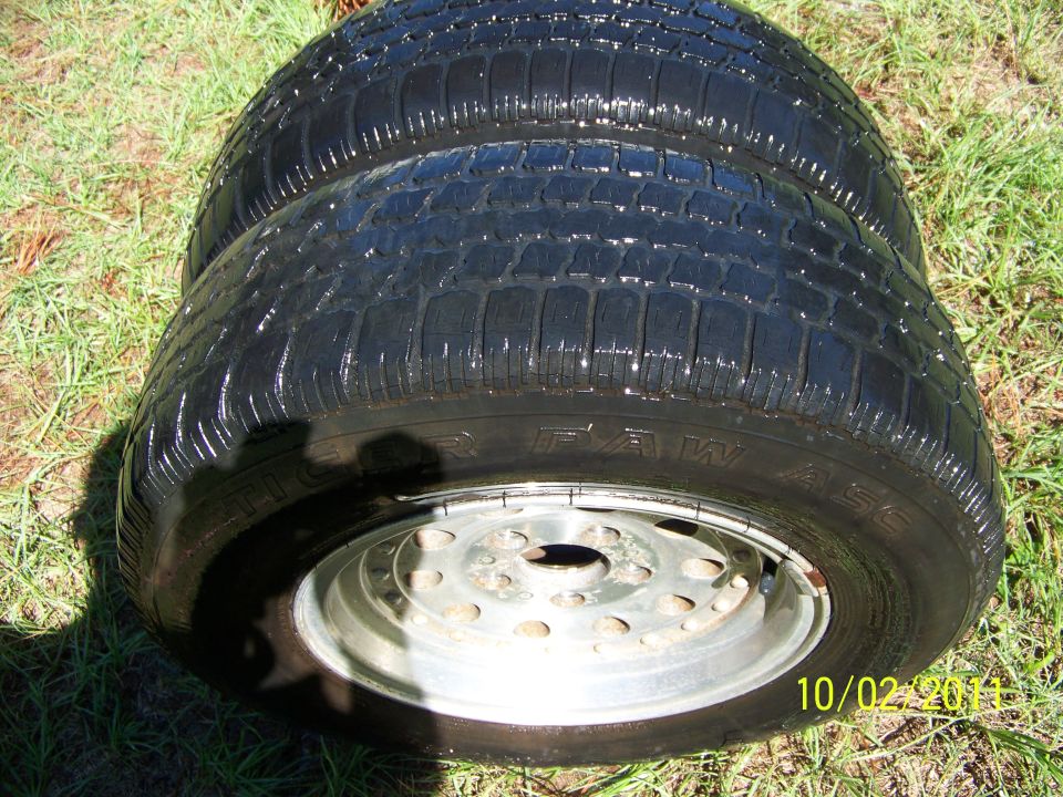 Two tires with rims are on the grass. Text on the tire says "Tiger Paw". Date stamp reads 10/02/2011