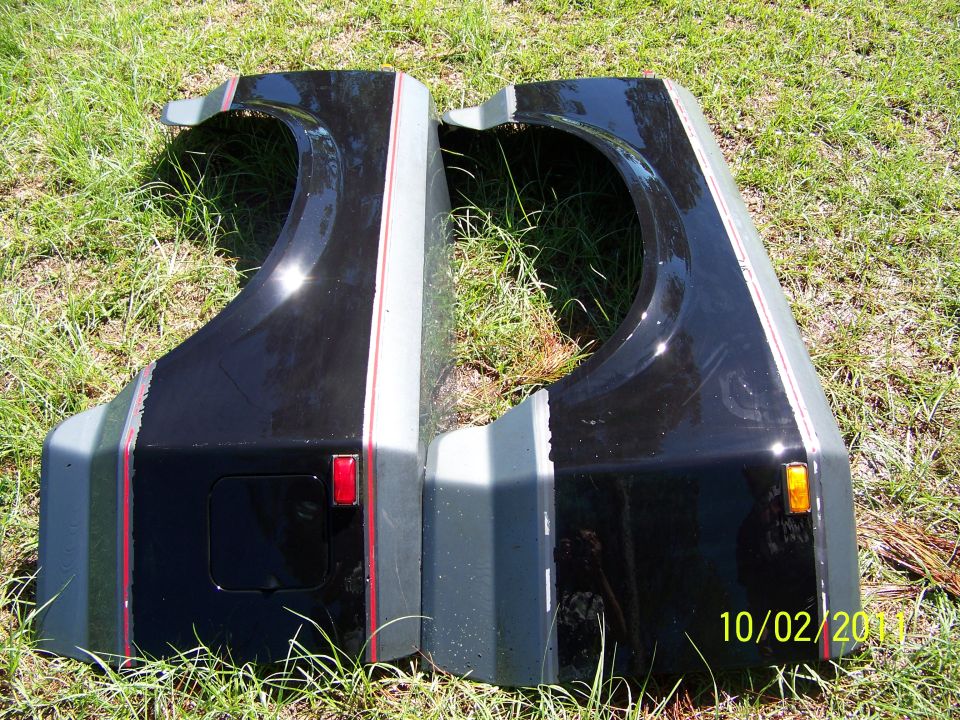 Two black fenders with grey and red stripe accents, one with a red reflector, the other with an amber marker light
