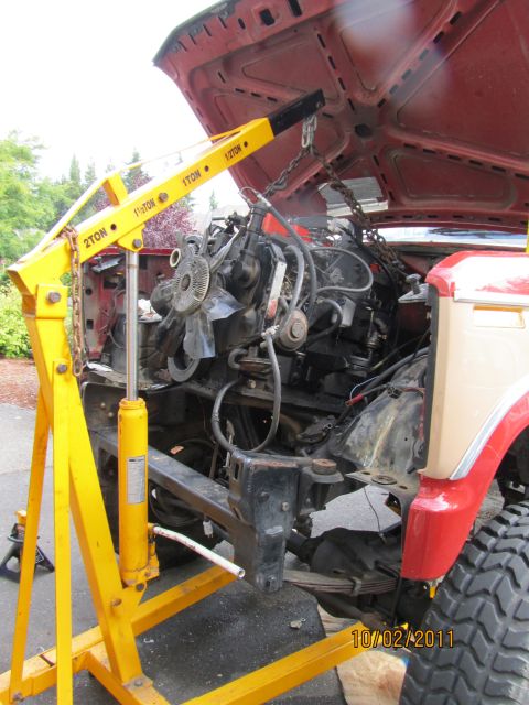 1984 Ford Bronco - Engine removal in progress on a 1984 Ford Bronco, aided by a yellow engine hoist.