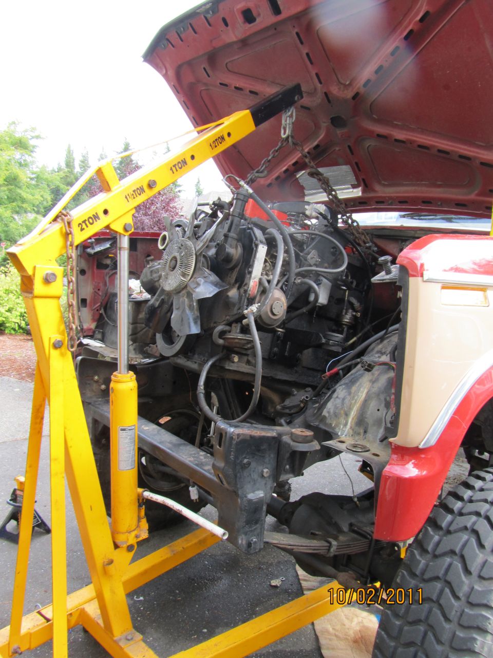 1984 Ford Bronco engine being removed with yellow engine hoist