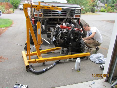 1984 Ford Bronco - A person works on removing the engine from a 1980 Ford Bronco using an engine hoist.