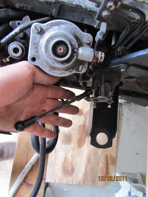1984 Ford Bronco - Close-up of a hand manipulating a linkage part within an engine bay, showing mechanical components.