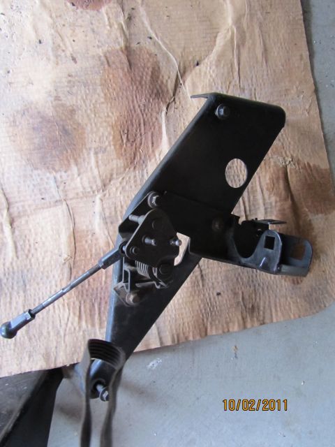 1984 Ford Bronco - A black clutch pedal assembly with linkage and spring is shown against a brown paper background. The date 10/02/2011 is visible.