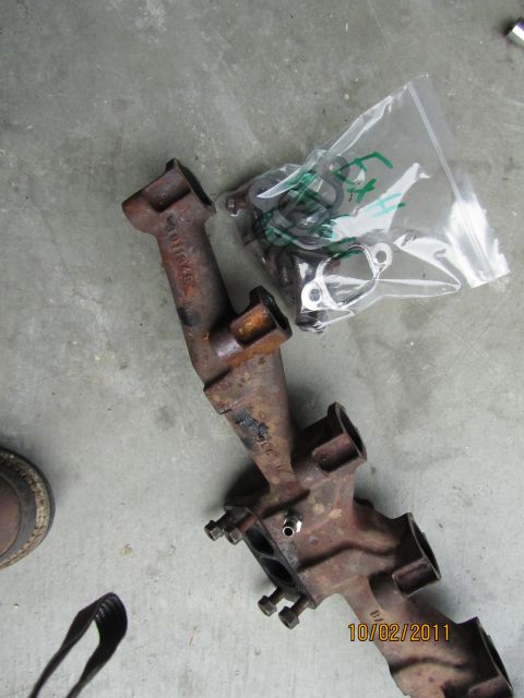 1984 Ford Bronco - Exhaust manifold and gasket kit shown on a concrete surface. Date stamp visible.