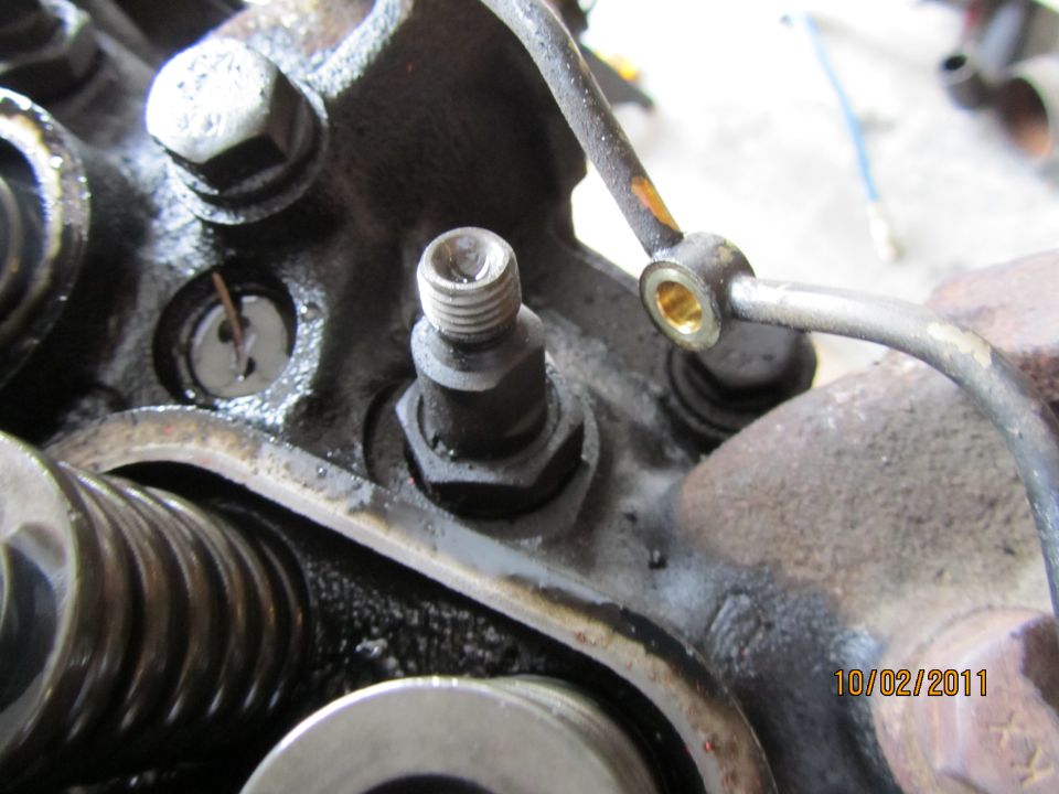 Close-up of engine valve train with oil residue and a metal fuel line