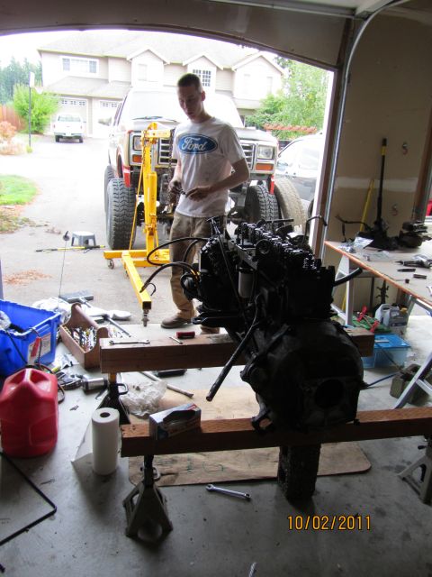 1984 Ford Bronco - A man is removing the engine from a Ford Bronco, which is supported by an engine hoist.